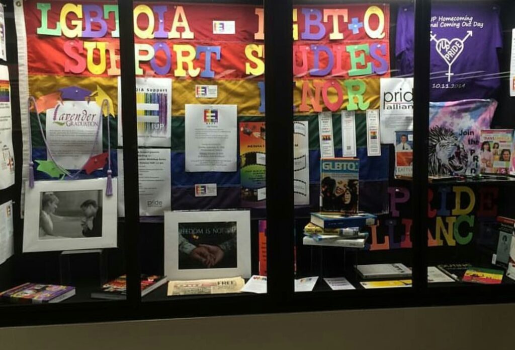 October is LGBT History Month; collage display representing various on campus LGBT affirming organizations. Dawn has two framed photos in this window display.